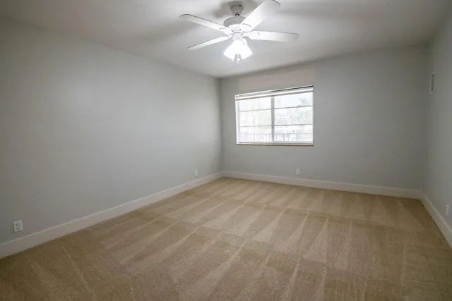 an empty room with a window and a fan