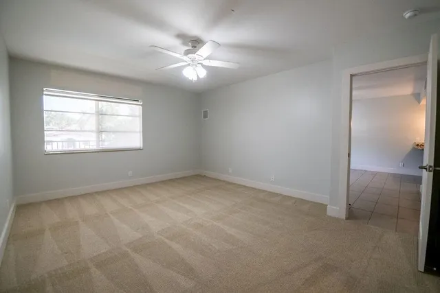 an empty room with windows and fan
