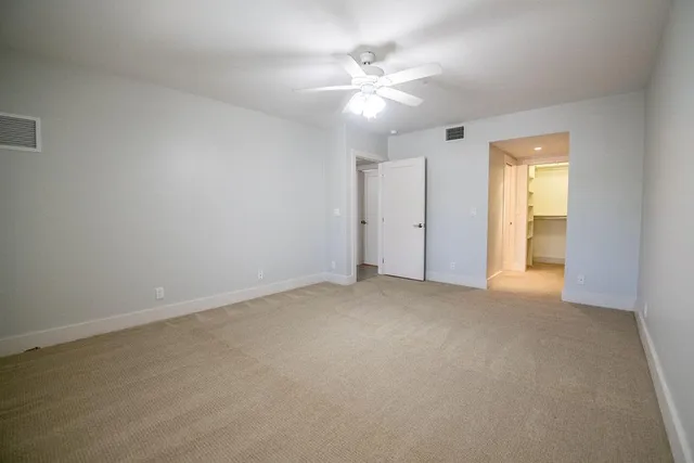 a view of an empty room with a chandelier fan