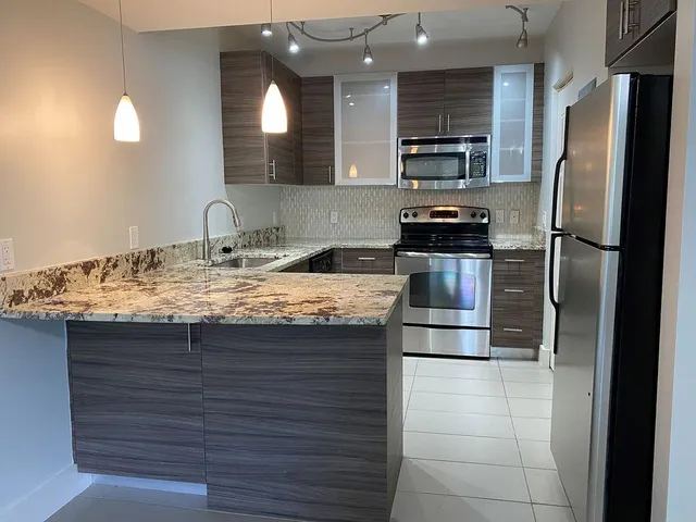 a kitchen with kitchen island granite countertop stainless steel appliances and refrigerator