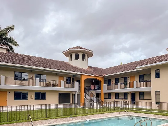 a front view of a building with glass windows and a yard