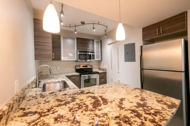 a kitchen with granite countertop a refrigerator stove and sink