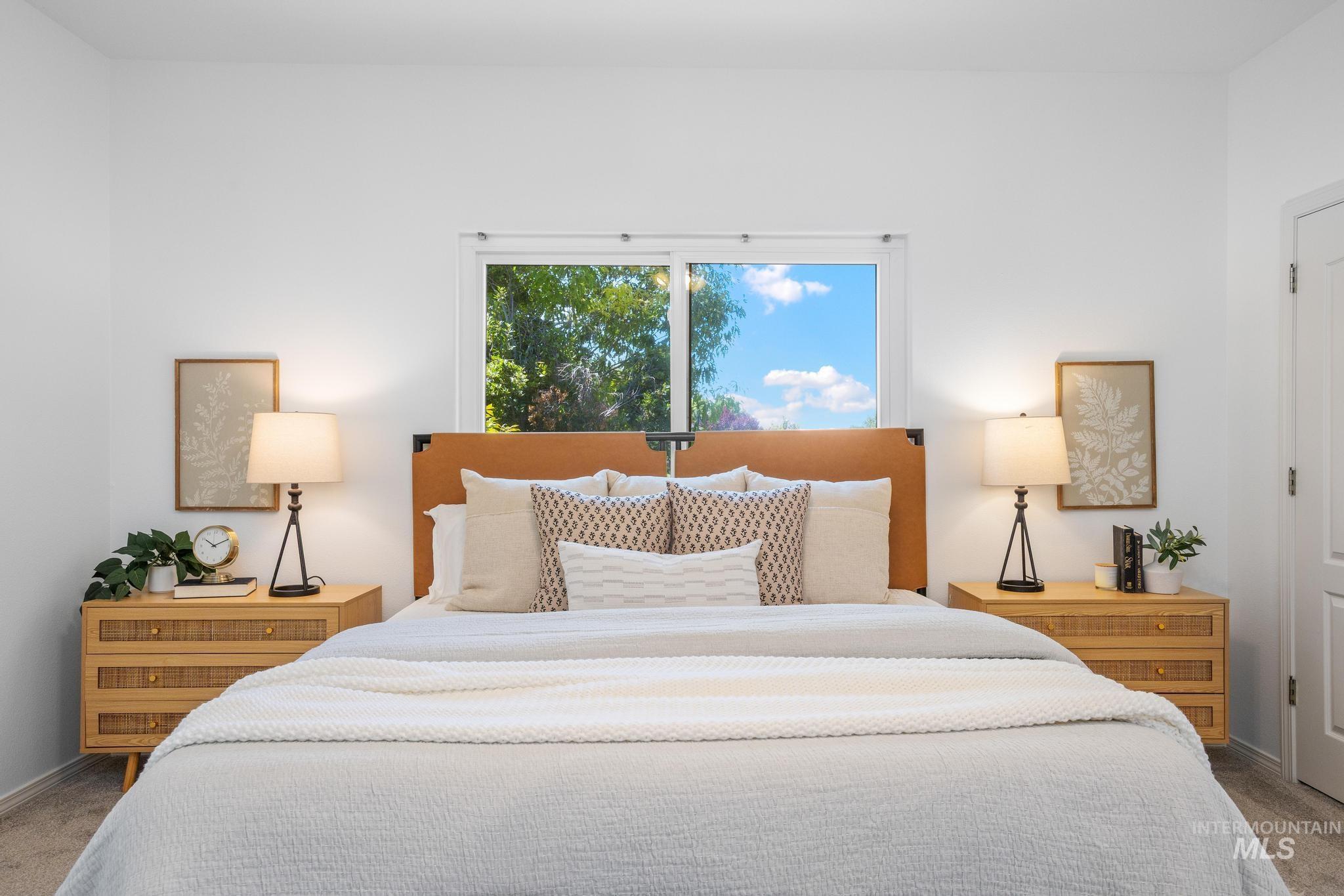 15181 Drury Way Caldwell, ID 83607 - Photo 21 of 49 Bright bedroom featuring a centered window, a leather-look headboard, and two matching wood nightstands with built-in drawers