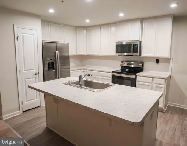 a kitchen with kitchen island a sink stainless steel appliances and cabinets