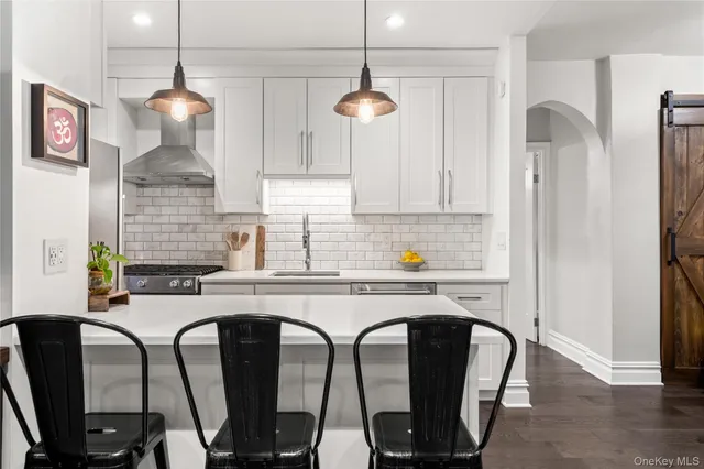 a kitchen with stainless steel appliances granite countertop a dining table chairs and a refrigerator