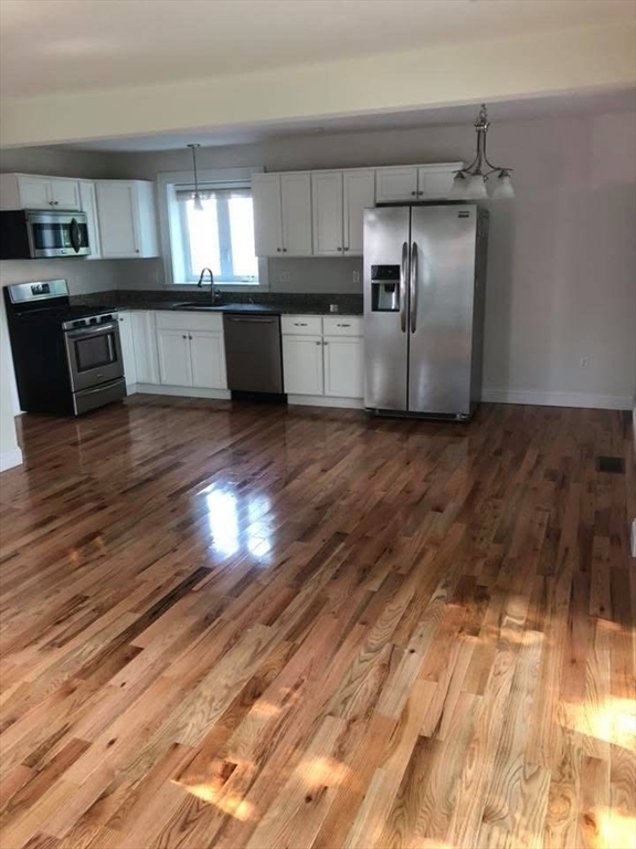 83.5 Market Street, Unit 83 5 Amesbury, MA 01913 - Photo 3 of 10 a kitchen with granite countertop a refrigerator and wooden floor