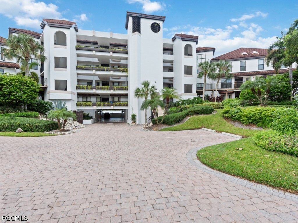 232 La Peninsula Boulevard, Unit 232 Naples, FL 34113 - Photo 32 of 44 a front view of a multi story residential apartment building with a yard
