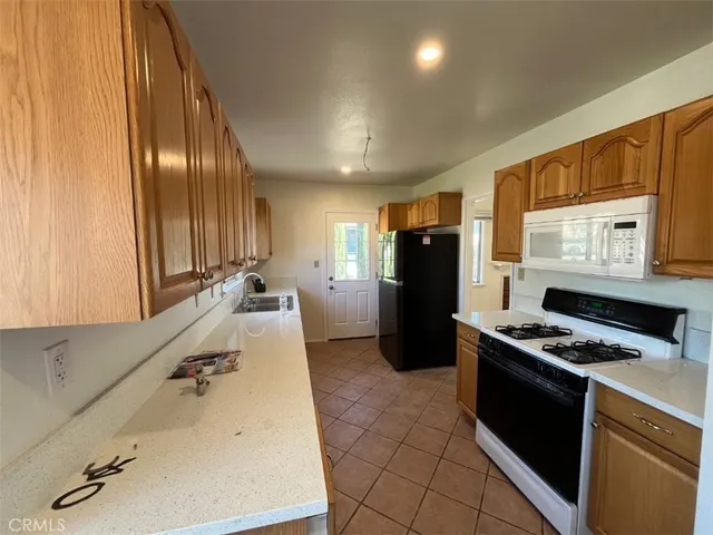 a kitchen with granite countertop stainless steel appliances a refrigerator stove top oven and sink