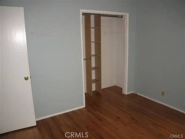 a view of an empty room with wooden floor and closet