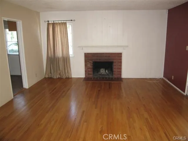 an empty room with wooden floor and fireplace