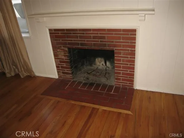 a view of an empty room with wooden floor and a fireplace