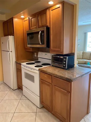 a kitchen with stainless steel appliances granite countertop a refrigerator a stove a sink and a microwave