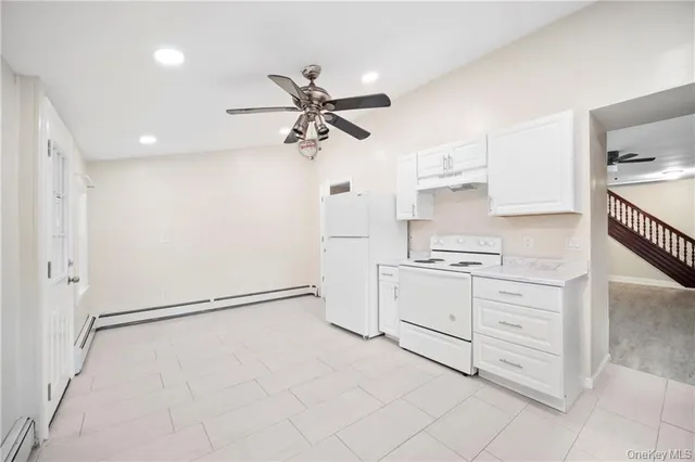 an empty room with wooden floor staircase and windows