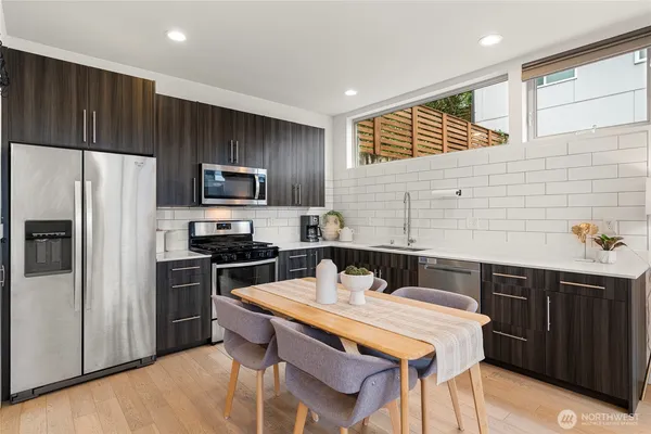 a kitchen with a refrigerator a stove a sink dishwasher with a dining table and chairs