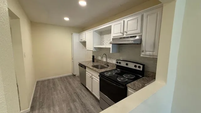 a kitchen with a stove and wooden floor