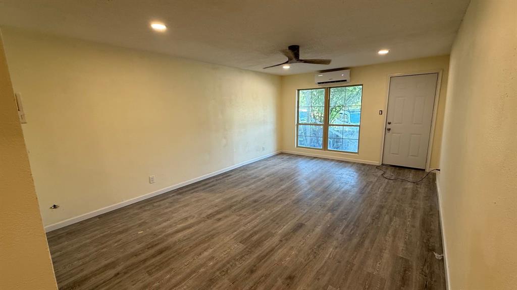 5065 Ridglea Lane, Unit 1009 Fort Worth, TX 76116 - Photo 4 of 12 an empty room with wooden floor and windows