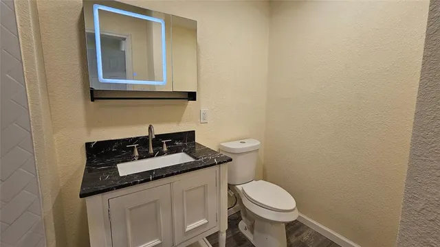 a bathroom with a granite countertop toilet and sink
