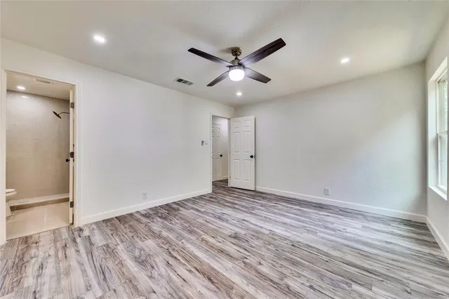 an empty room with wooden floor and a ceiling fan