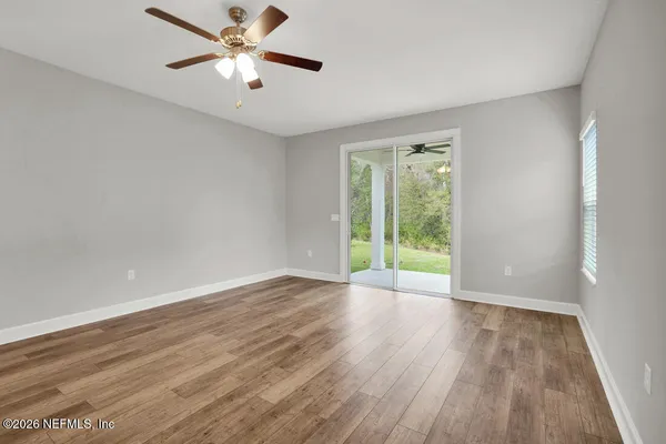 a view of an empty room with window and wooden floor