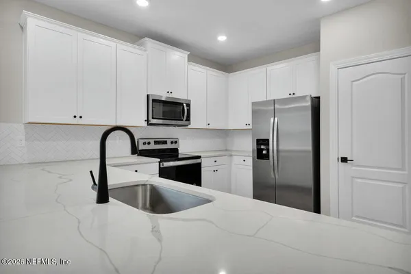 a kitchen with a refrigerator a microwave a sink and cabinets