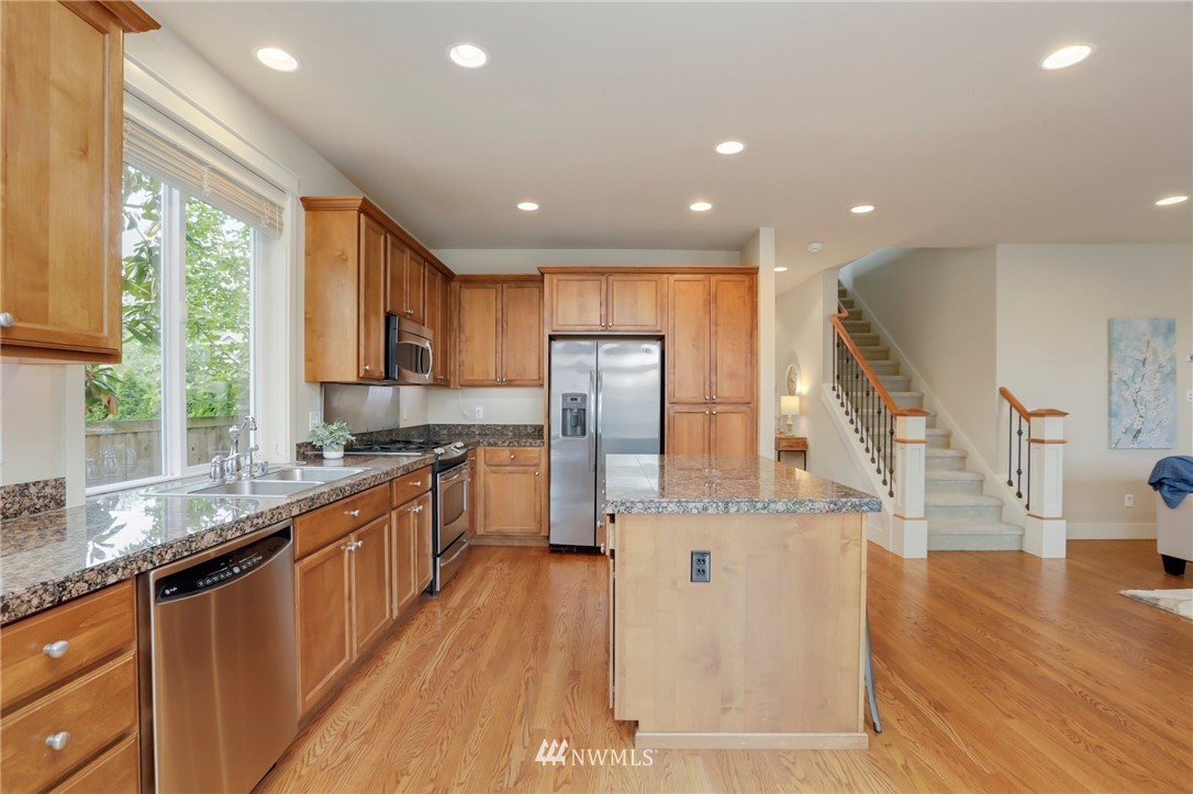 4014 167th Street Southeast Bothell, WA 98012 - Photo 13 of 39 a kitchen with stainless steel appliances granite countertop a refrigerator a sink dishwasher a stove and a dining table with wooden floor