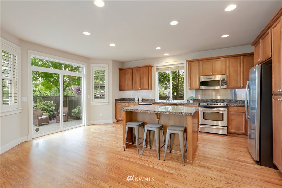 4014 167th Street Southeast Bothell, WA 98012 - Photo 15 of 39 a kitchen with stainless steel appliances granite countertop a stove top oven a sink dishwasher a dining table and chairs with wooden floor
