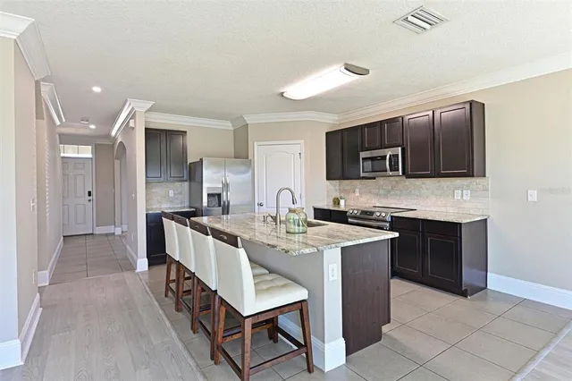 a large kitchen with a stove a sink a microwave and a refrigerator