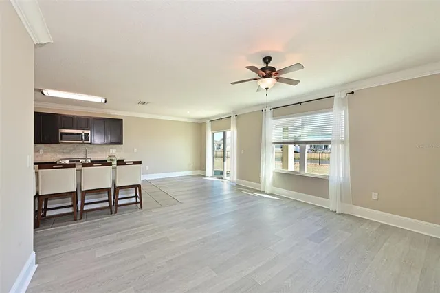 a view of an empty room with a kitchen and a window