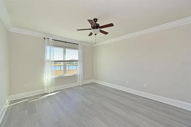 an empty room with wooden floor ceiling fan and windows