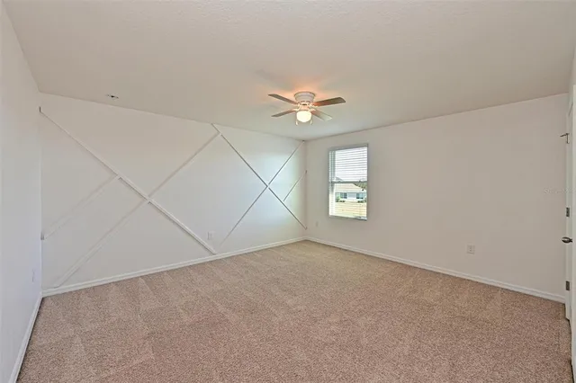 an empty room with a window and a ceiling fan