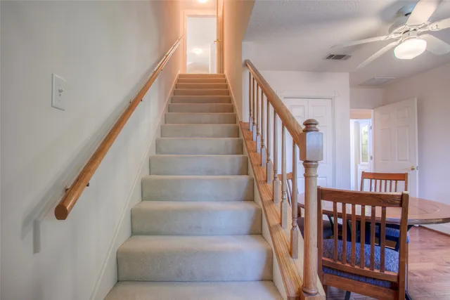 a view of staircase with lots of frames on wall and wooden floor