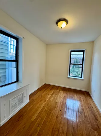 a view of an empty room with window and wooden floor