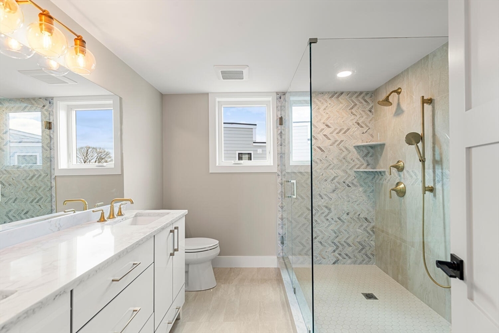 312 Newton Street, Unit 1A Waltham, MA 02453 - Photo 26 of 32 a bathroom with a shower sink vanity mirror and toilet