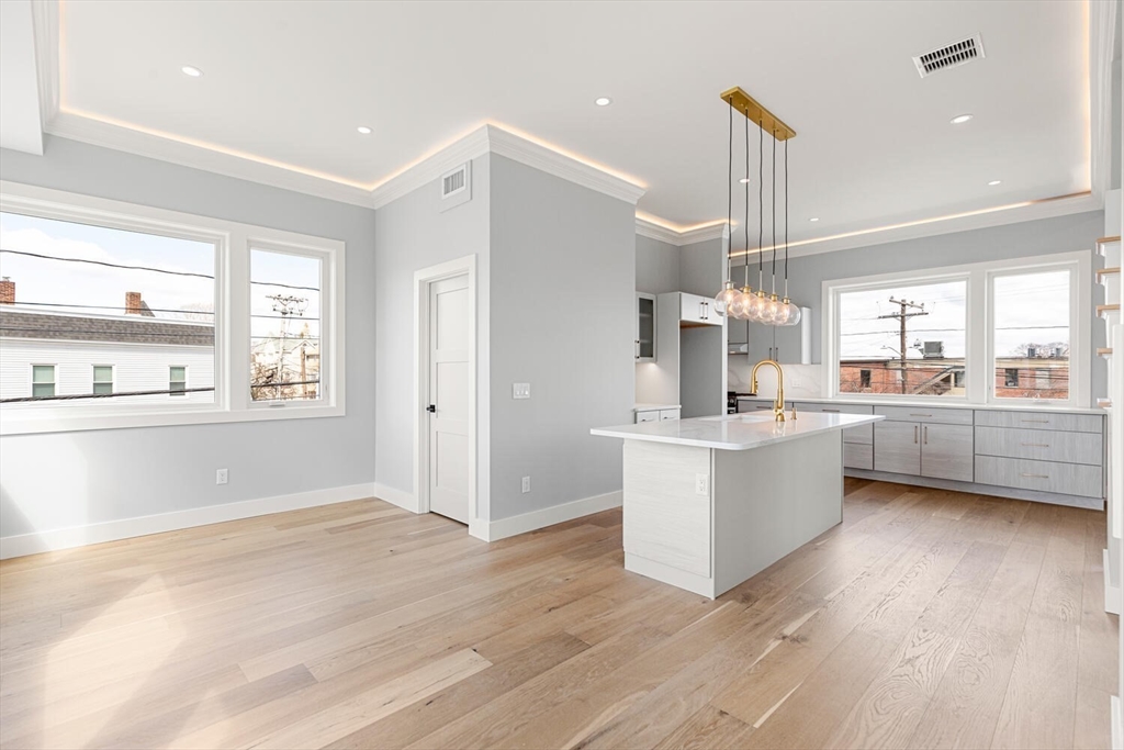 312 Newton Street, Unit 1A Waltham, MA 02453 - Photo 7 of 32 a kitchen with stainless steel appliances kitchen island wooden floors and white cabinets