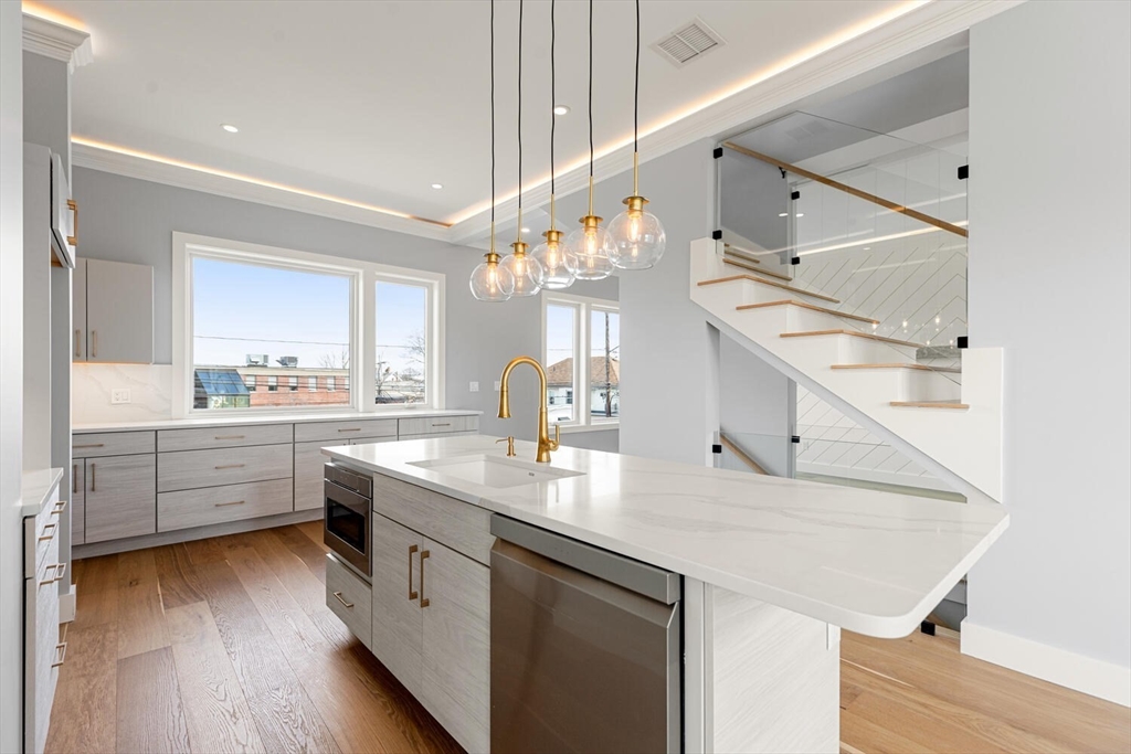312 Newton Street, Unit 1A Waltham, MA 02453 - Photo 9 of 32 a kitchen with a sink dishwasher a stove and white cabinets with wooden floor