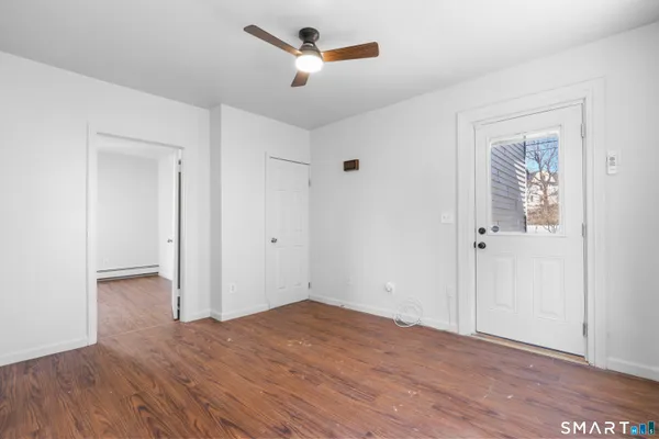 an empty room with wooden floor and a ceiling fan
