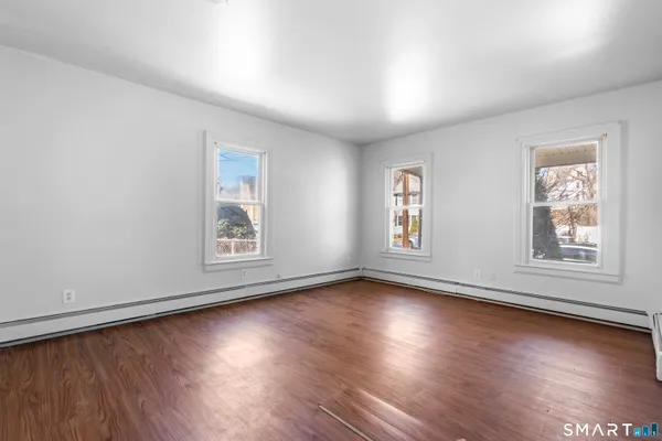 a view of an empty room with wooden floor and a window