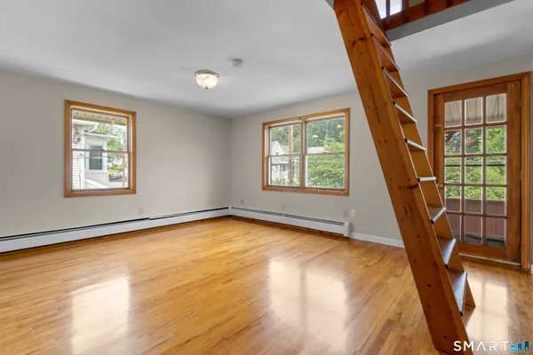 a view of an empty room with wooden floor and a window