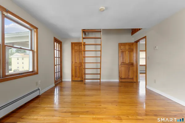 a view of empty room with wooden floor and fan