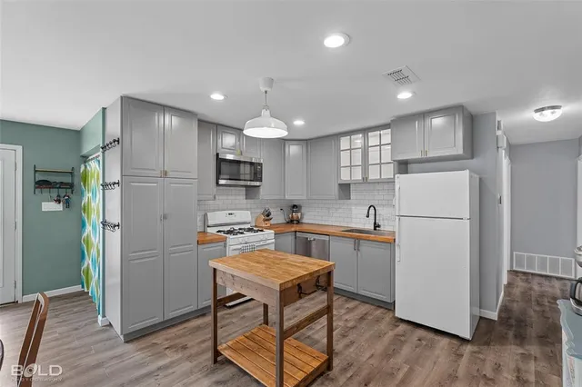 a kitchen with a refrigerator a microwave oven a sink dishwasher and white cabinets with wooden floor