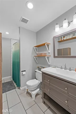 a bathroom with a granite countertop toilet sink and mirror