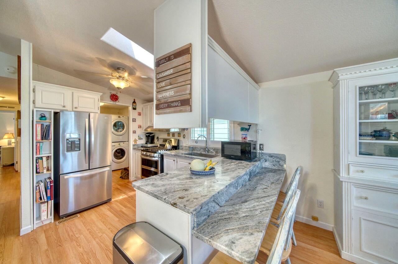 5 Lighthouse Road, Unit 5 Half Moon Bay, CA 94019 - Photo 11 of 25 a kitchen with granite countertop a refrigerator a stove and white cabinets with wooden floors
