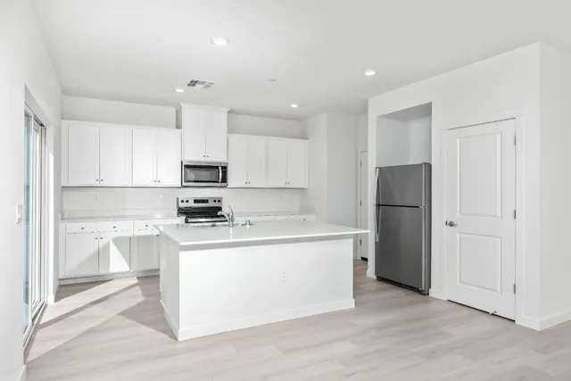 a kitchen with a refrigerator a stove top oven and white cabinets