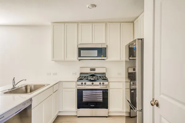 a kitchen with white cabinets and appliances