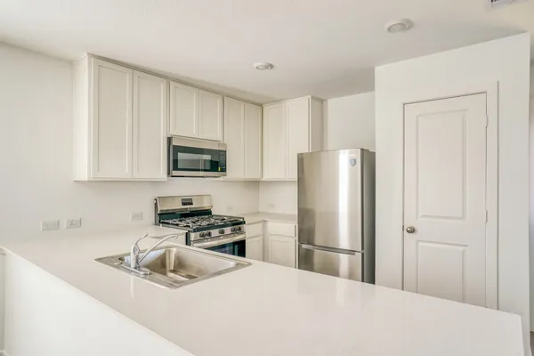 a kitchen with stainless steel appliances granite countertop a refrigerator stove top oven a sink and dishwasher