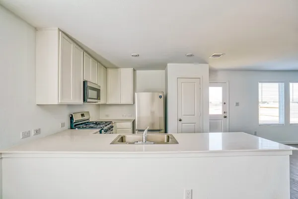 a kitchen with stainless steel appliances granite countertop a sink a refrigerator and a white cabinets