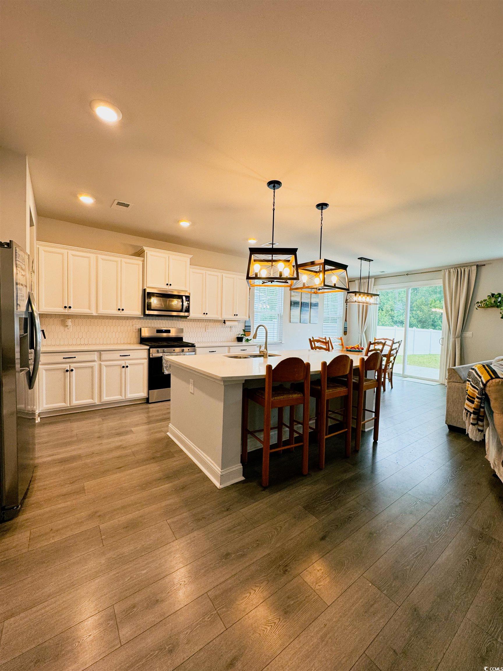 109 Maidenhair Loop Myrtle Beach, SC 29579 - Photo 6 of 39 Kitchen featuring a kitchen bar, a center island with sink, decorative light fixtures, appliances with stainless steel finishes, and white cabinetry