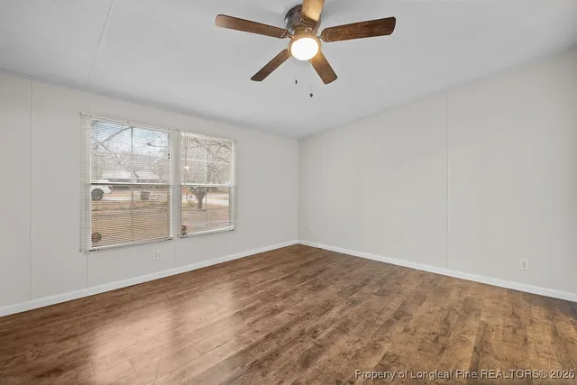 an empty room with chandelier fan and windows