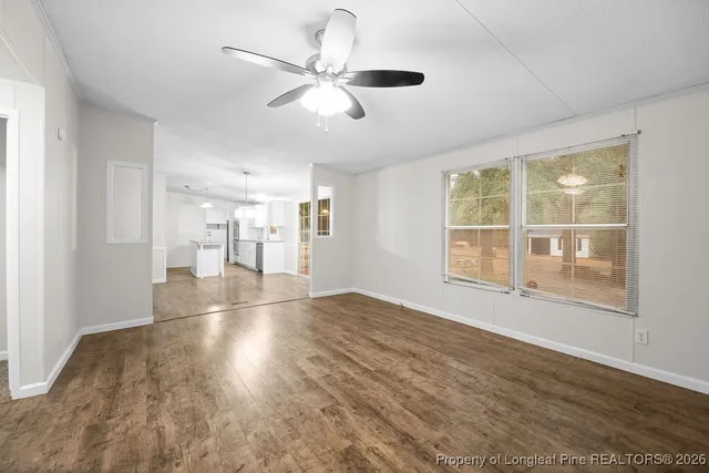 a view of empty room with wooden floor and fan