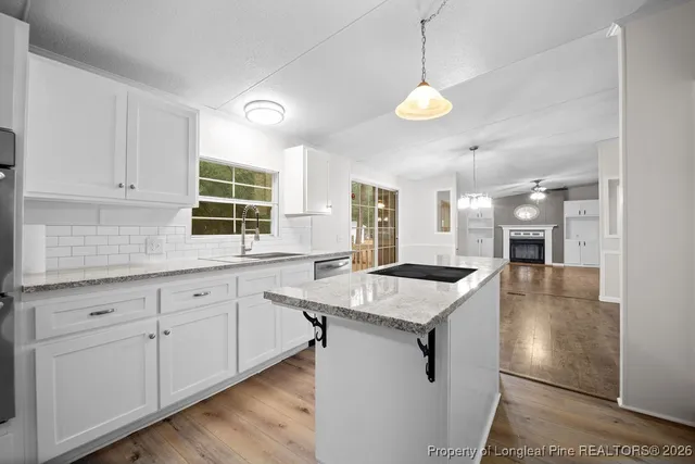 a kitchen with a stove center island a window and cabinets